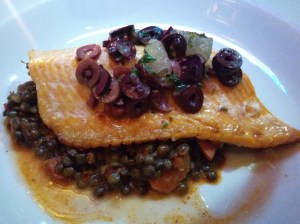 Omble chevalier au beurre noir et olives noires, servi sur un lit de lentilles et de chorizo.